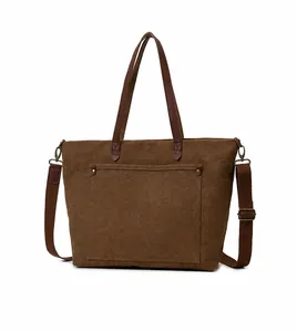 Detalle del bolso tote de lona marrón con asas de cuero y bolsillo frontal grande