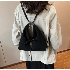 Macro detail of black frosted leather backpack with decorative drawstring bow
