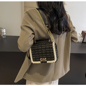 Detail of tweed crossbody bag with pearl trim and gold chain strap shown on a model