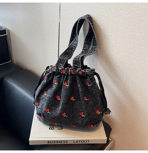 Close-up of deep grey washed denim bucket bag with detailed red cherry embroidery