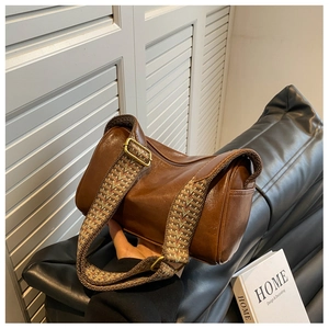 Detail of vintage brown boston bag with textured wide strap and brass hardware