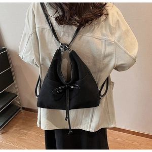 Back view of a model wearing a black matte tote bag with glossy bow and thin straps
