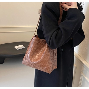 Vue détaillée d'un sac seau tressé marron avec texture en cuir et bandoulière