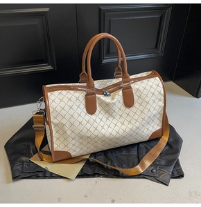 Makro-Detail der beigen Reisetasche mit braunem Rautenmuster und Premium-Ledergriffen