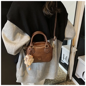 Detail of vintage brown crossbody bag with leather handles and cute plush bear charm