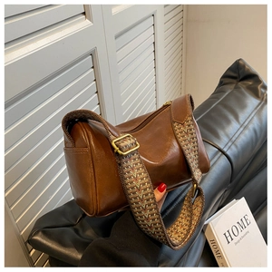 Detail of brown leather cylinder bag with wide ethnic geometric woven strap and side pocket