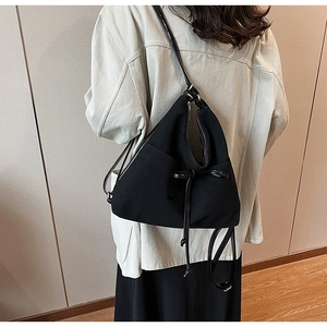 Detail of a large black canvas hobo bag with drawstring and zipper on shoulder