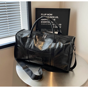 Detalle de bolsa de deporte negra grande con textura arrugada brillante y correa