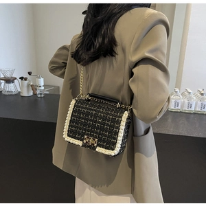 Elegant black tweed shoulder bag with pearl trim and chain strap on female model