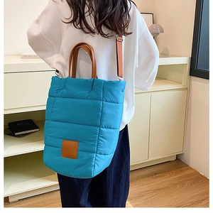 Quilted blue bucket bag detail with brown leather strap and padded texture finish