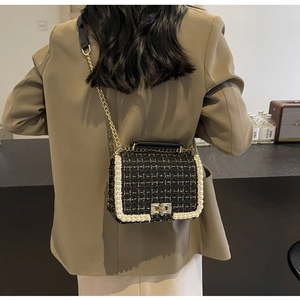 Model wearing tweed crossbody bag with pearl trim and gold chain strap over a blazer