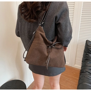 Brown suede tote bag shown on shoulder featuring elegant ribbon drawstring and large capacity