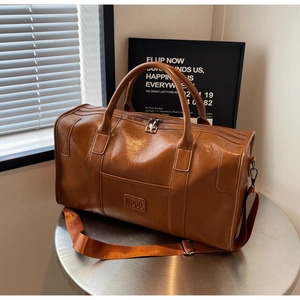 Detalle de bolsa de viaje marrón con logo NOCO grabado y correa de nailon para el hombro