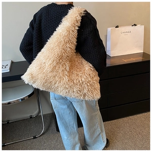 Detailed back view of a large fluffy faux fur tote bag in beige worn by a model
