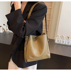 Gros plan du sac seau en cuir tressé vert olive avec large bandoulière sur un mannequin