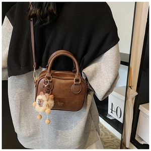 Detailed side view of vintage brown leather handbag with a cute white sheep charm