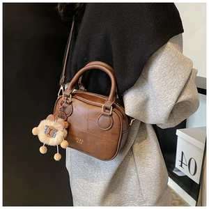 Detail of vintage brown crossbody bag with geometric stitching and plush bear charm