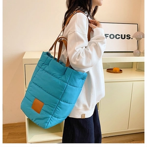 Detailed side view of bright blue quilted bucket bag with brown leather shoulder strap