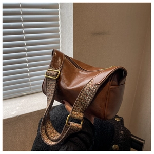 Macro shot of vintage dark brown leather pillow bag with colorful woven wide strap