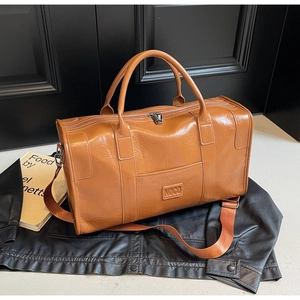 Detalle del bolso de viaje NOGO de cuero marrón con logotipo sobre chaqueta de cuero