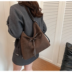 Detail of vintage brown suede hobo bag with bow tie on model for daily commute