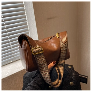 Close-up of vintage brown pillow bag featuring golden zipper and ethnic woven strap