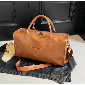 Detalle de bolsa de viaje marrón con textura de lichi y correa sobre una chaqueta