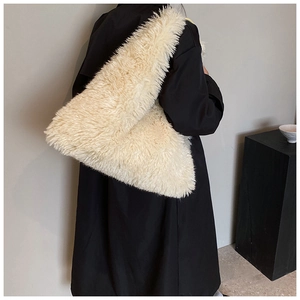 Detailed side view of the cream faux fur shoulder bag worn by a model in a black coat
