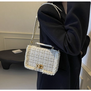 Detail of tweed crossbody bag with pearl trim, gold chain, and metal turn-lock closure