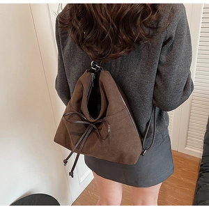 Detail of dark brown drawstring backpack with a leather bow and matte finish texture