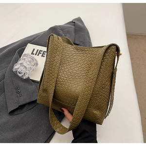 Détail de la texture en cuir tressé vert olive d'un sac seau élégant avec bandoulière large