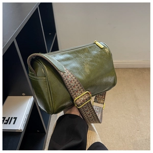 Detail of forest green boston bag featuring vintage leather texture and wide woven strap