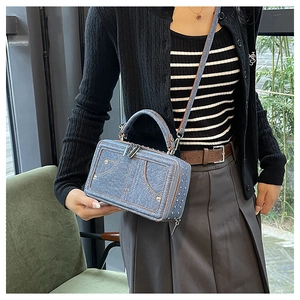 Detailansicht der Umhängetasche aus Denim mit Metallnieten und modischen Kontrastnähten