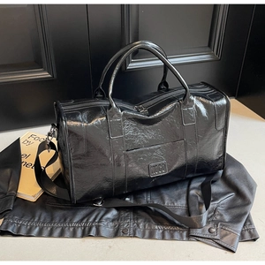 Detalle de bolsa de viaje grande negra brillante con logo NOCO y asas reforzadas