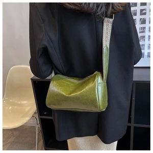 Detail view of grass green boston bag with textured faux leather and ethnic woven strap