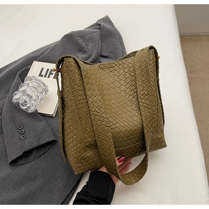 Détail de la texture tissée vert foncé d'un sac seau élégant avec bandoulière large