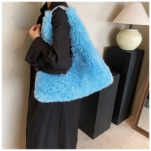 Close-up of a large electric blue plush tote bag styled on a model's shoulder over a black coat