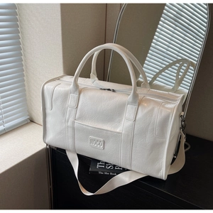 Detalle de un bolso de viaje NOCO blanco con textura de cuero plisado y correa ancha