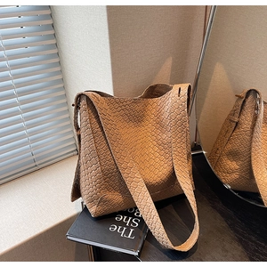Détail du sac cabas marron à texture tressée avec bandoulière sur un comptoir