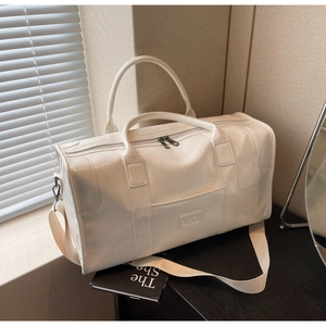 Detalle de bolsa de viaje de cuero blanco con logo NOCO grabado y correa ajustable