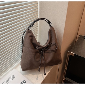 Detailed shot of retro brown tote bag with leather bow decoration and suede texture