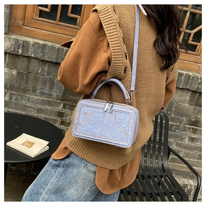 Straßenstil-Ansicht einer hellblauen Umhängetasche in Jeans-Optik mit silbernen Metallnieten