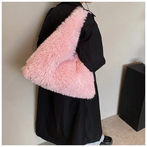 Model wearing large pink fuzzy faux fur tote bag paired with a long black winter coat