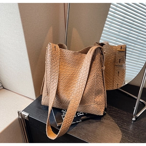 Détail de la texture tressée du sac seau kaki avec motif de cuir croisé de haute qualité