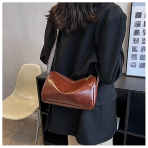 Detail of dark brown cylindrical crossbody bag with trendy wide patterned strap