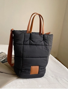 Black quilted bucket bag with brown leather handles and adjustable shoulder strap
