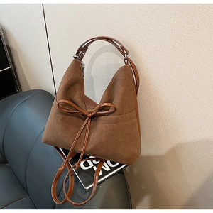 Detailed view of the brown suede tote bag with elegant bow tie decoration and leather handles