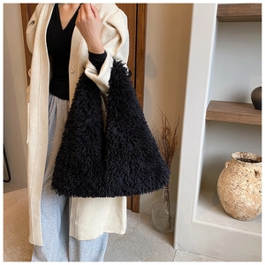 Large black plush faux fur tote bag styled in a cozy interior setting for autumn fashion