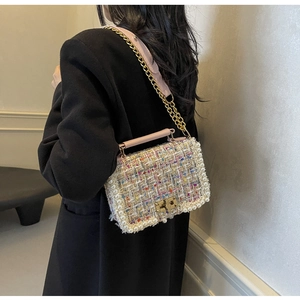 Detail of tweed crossbody bag featuring pearl trim and gold chain strap on a model