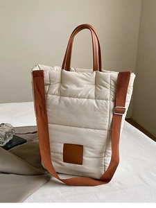 Minimalist ivory quilted bucket bag with brown leather handles and woven shoulder strap